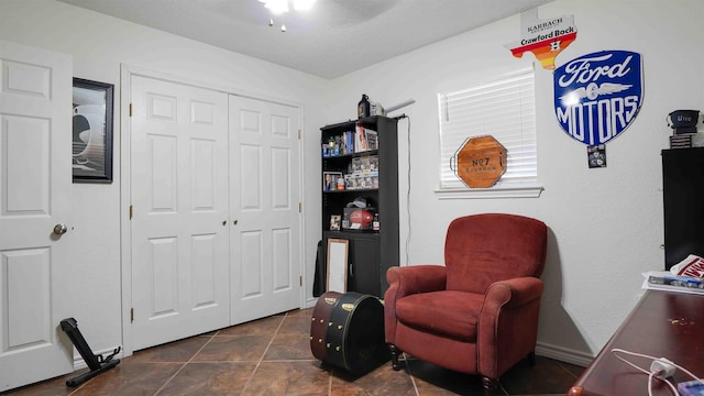 sitting room featuring ceiling fan and dark tile patterned flooring