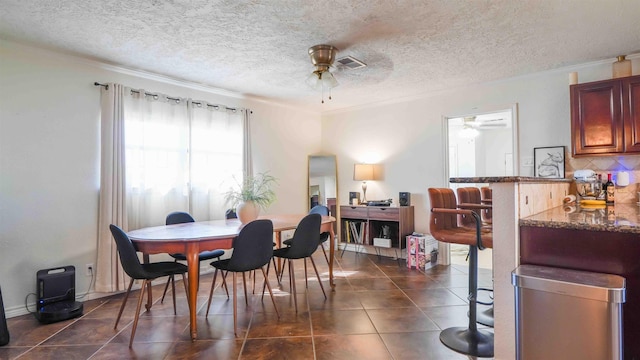 tiled dining room with a textured ceiling, ceiling fan, and ornamental molding