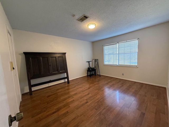 unfurnished room featuring a textured ceiling and dark wood-type flooring