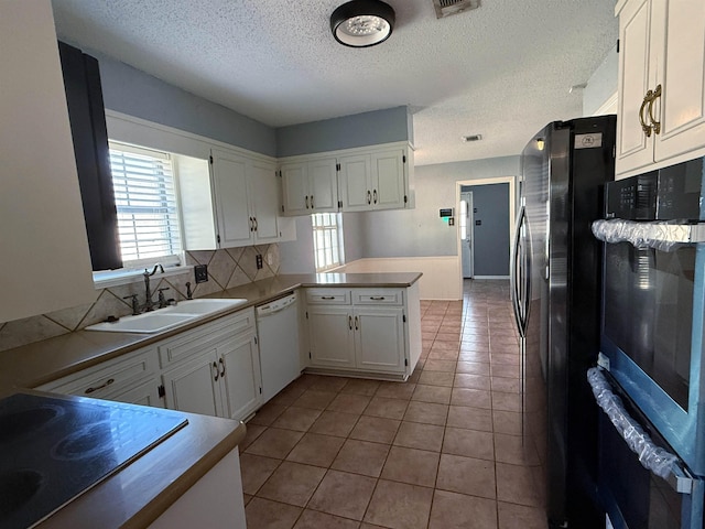 kitchen featuring kitchen peninsula, sink, black appliances, light tile patterned floors, and white cabinets