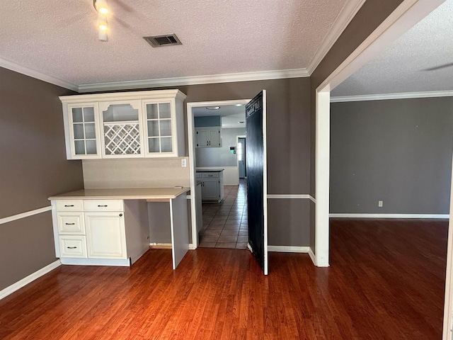 kitchen featuring a textured ceiling, built in desk, white cabinetry, and dark wood-type flooring