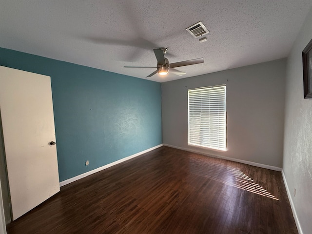 empty room with ceiling fan, dark hardwood / wood-style flooring, and a textured ceiling