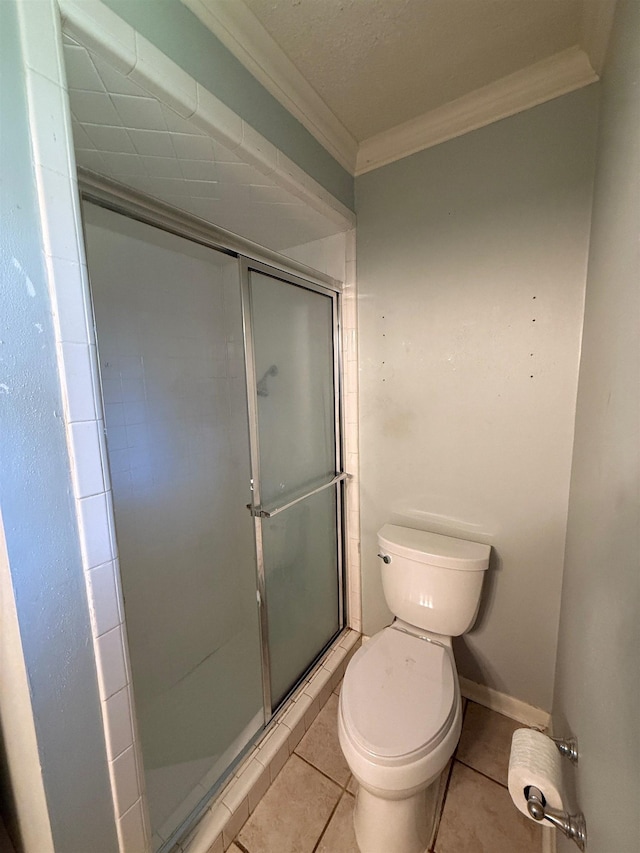 bathroom featuring tile patterned floors, crown molding, a shower with door, and toilet