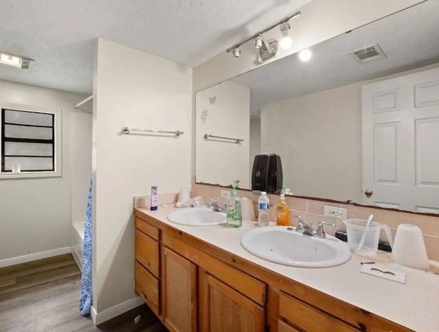 19995 S Fm 92, Fred, TX 77616 - full bath featuring wood finished floors, double vanity, a textured ceiling, and shower / bathtub combination with curtain