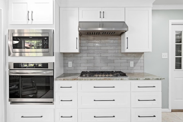 935 Nichols Dr, Beaumont, TX 77706 - kitchen with stainless steel appliances, wall chimney exhaust hood, light stone countertops, tasteful backsplash, and white cabinets