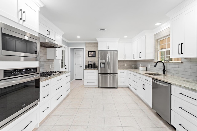 935 Nichols Dr, Beaumont, TX 77706 - kitchen with stainless steel appliances, tasteful backsplash, ornamental molding, white cabinetry, and light stone counters