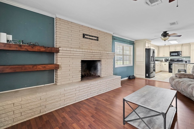 living area featuring a brick fireplace, light wood finished floors, and ceiling fan