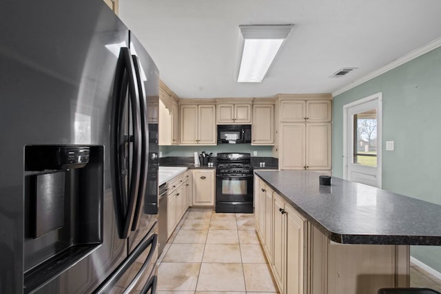 kitchen featuring visible vents, black appliances, cream cabinetry, dark countertops, and a center island