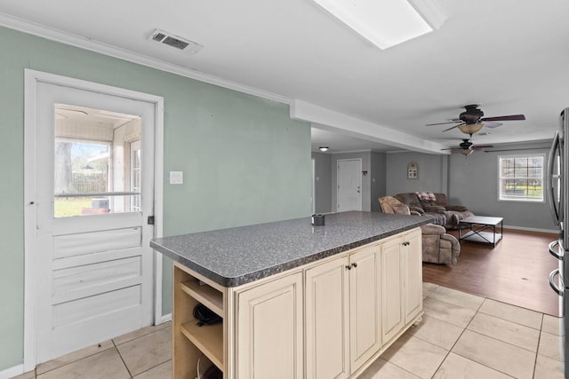 kitchen with dark countertops, visible vents, cream cabinetry, and light tile patterned floors