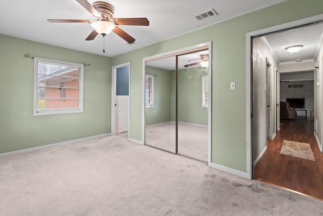 unfurnished bedroom featuring crown molding, carpet flooring, visible vents, and a closet