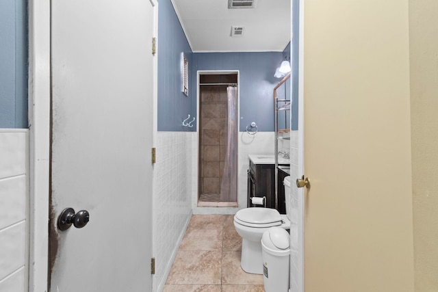 bathroom featuring vanity, visible vents, a stall shower, tile walls, and toilet