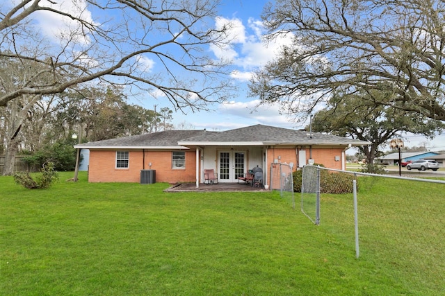 rear view of property with brick siding, cooling unit, french doors, and a lawn