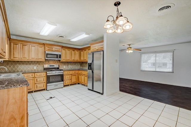 kitchen with pendant lighting, sink, appliances with stainless steel finishes, light tile patterned flooring, and decorative backsplash