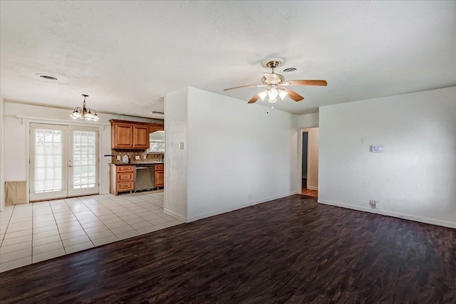 unfurnished living room with ceiling fan with notable chandelier, light hardwood / wood-style floors, french doors, and a textured ceiling