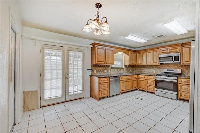 kitchen featuring light tile patterned floors, decorative backsplash, stainless steel appliances, and dark stone counters