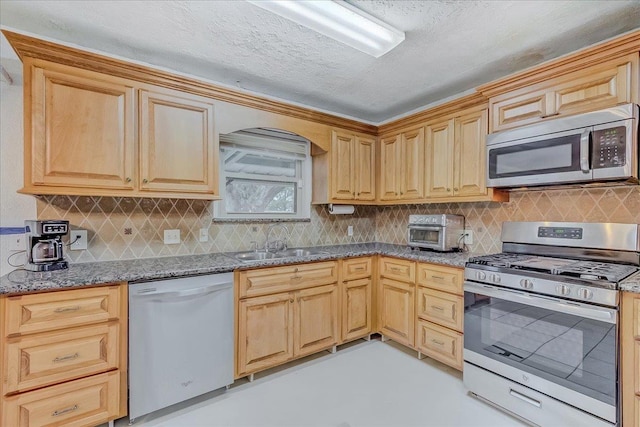 kitchen featuring light stone counters, sink, decorative backsplash, and appliances with stainless steel finishes