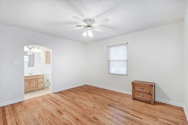 unfurnished bedroom with connected bathroom, sink, ceiling fan, a textured ceiling, and light hardwood / wood-style flooring