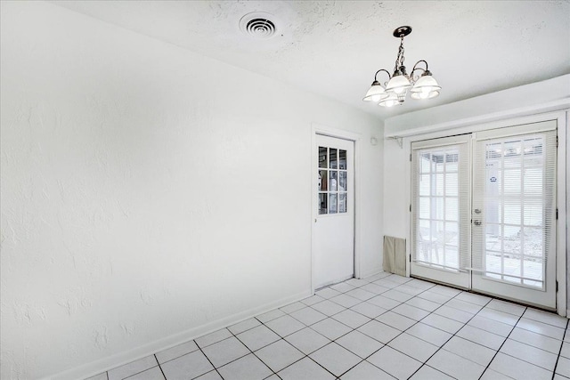 tiled spare room with a textured ceiling and a chandelier