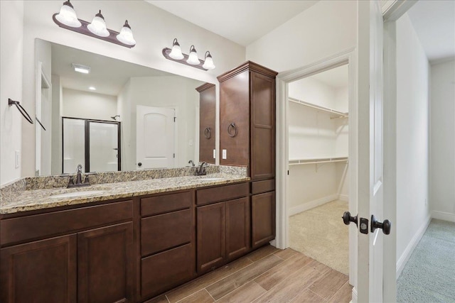 4406 Sequoia, Orange, TX 77630 - bathroom with a stall shower, wood finished floors, double vanity, a walk in closet, and baseboards