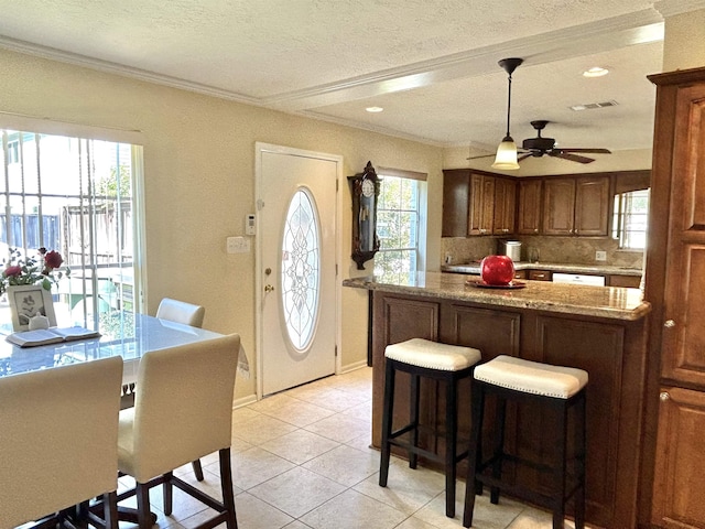 kitchen with light stone counters, a textured ceiling, ceiling fan, crown molding, and light tile patterned flooring