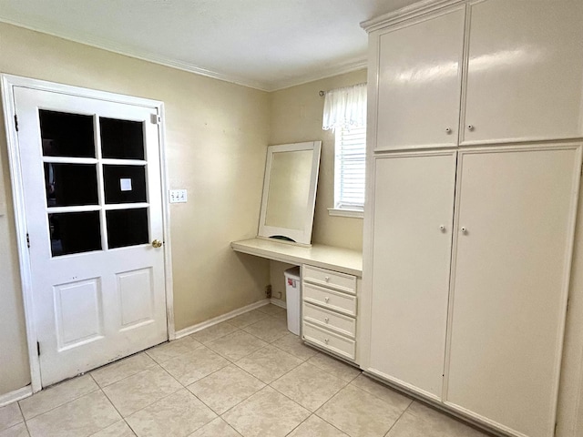 interior space featuring built in desk, crown molding, and light tile patterned floors