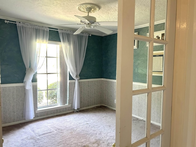 empty room with carpet flooring, ceiling fan, and a textured ceiling