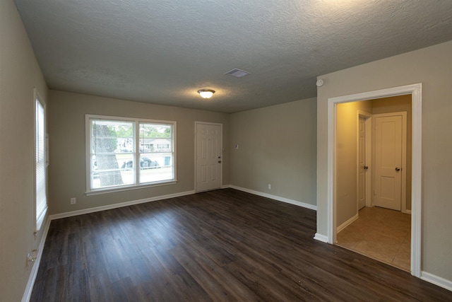 empty room with a textured ceiling and dark hardwood / wood-style flooring