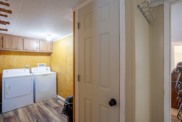 laundry area featuring cabinets, a textured ceiling, light hardwood / wood-style floors, and washing machine and clothes dryer