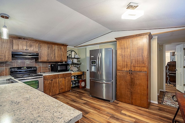 kitchen with backsplash, vaulted ceiling, stainless steel fridge, decorative light fixtures, and electric range oven