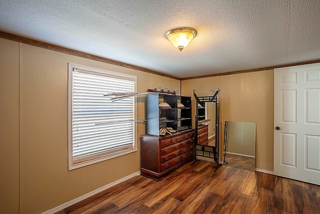 bedroom featuring dark hardwood / wood-style flooring, a textured ceiling, and ornamental molding