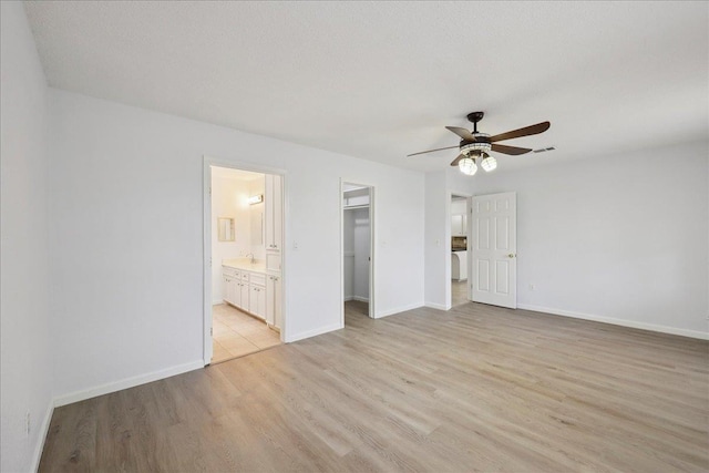 1336 Beagle Rd, Orange, TX 77632 - unfurnished bedroom with light wood-style floors, a spacious closet, connected bathroom, a closet, and ceiling fan