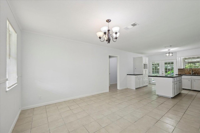 1336 Beagle Rd, Orange, TX 77632 - kitchen with dark countertops, a center island, white cabinets, a chandelier, and decorative light fixtures