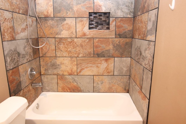 bathroom with toilet and tiled shower / bath