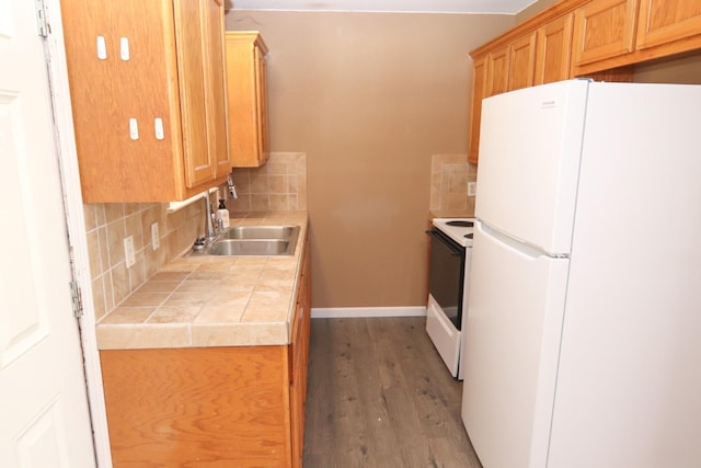 kitchen featuring sink, white appliances, hardwood / wood-style floors, tile counters, and backsplash