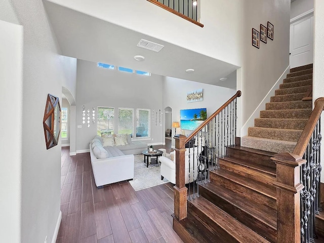 10340 Dominion Ranch Dr, Port Arthur, TX 77640 - stairs featuring arched walkways, a towering ceiling, wood finished floors, and baseboards
