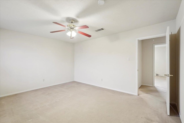 spare room featuring a ceiling fan, baseboards, visible vents, and light carpet