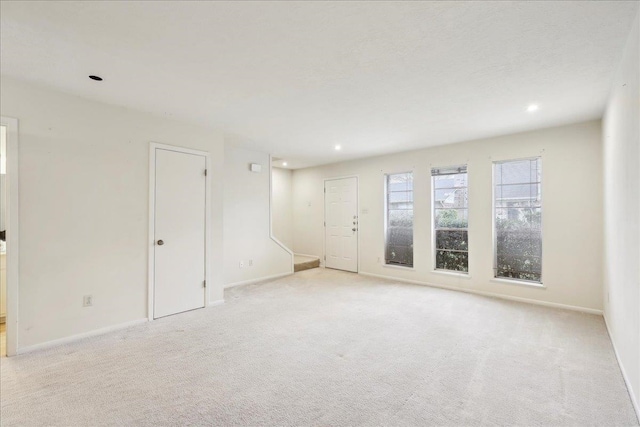 spare room featuring recessed lighting, baseboards, and light colored carpet