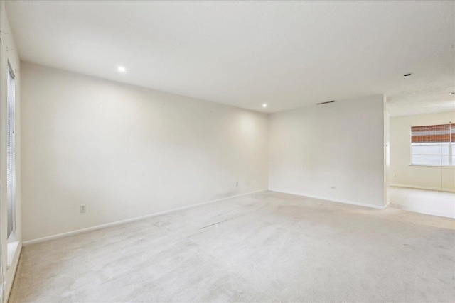 empty room with recessed lighting, light colored carpet, visible vents, and baseboards