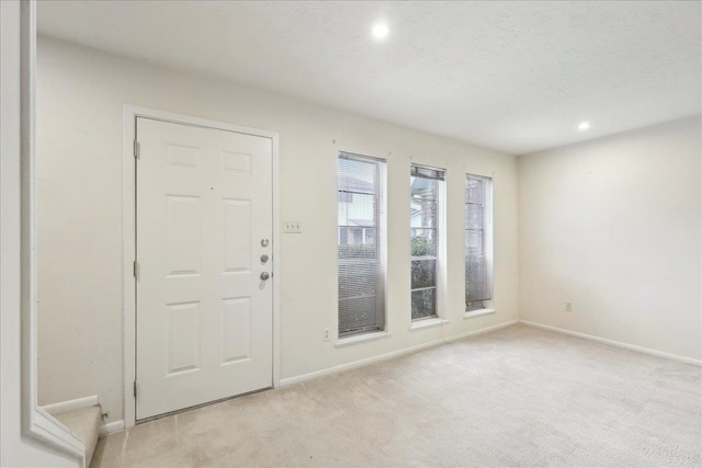 foyer with a textured ceiling, recessed lighting, baseboards, and light carpet