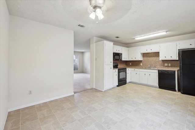 kitchen with visible vents, black appliances, a sink, backsplash, and white cabinets