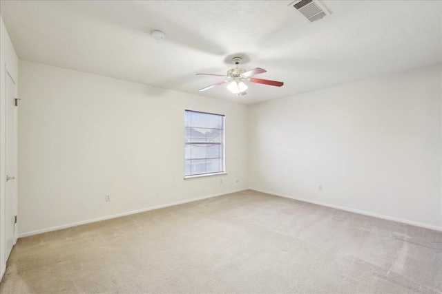 spare room featuring ceiling fan, baseboards, visible vents, and light carpet