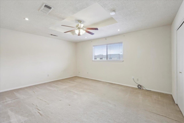 spare room featuring light colored carpet, visible vents, and a textured ceiling