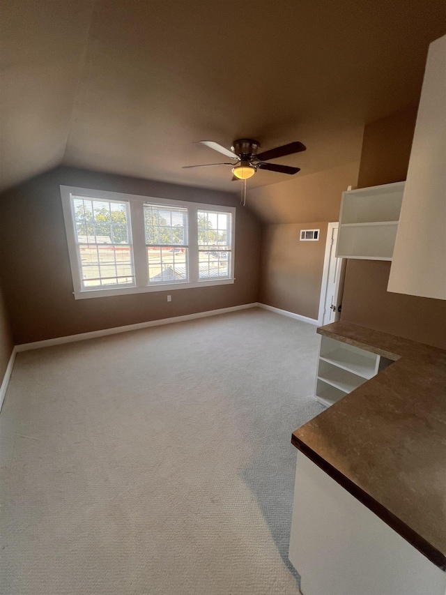 unfurnished living room featuring light colored carpet, vaulted ceiling, and ceiling fan