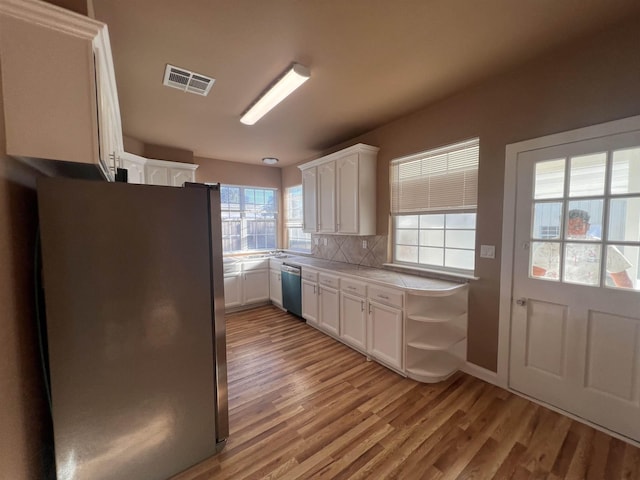 kitchen with white cabinets, appliances with stainless steel finishes, light hardwood / wood-style flooring, and tasteful backsplash