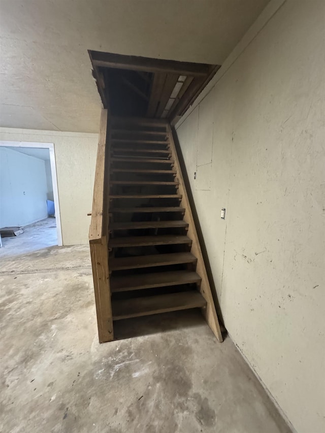 stairway featuring unfinished concrete floors