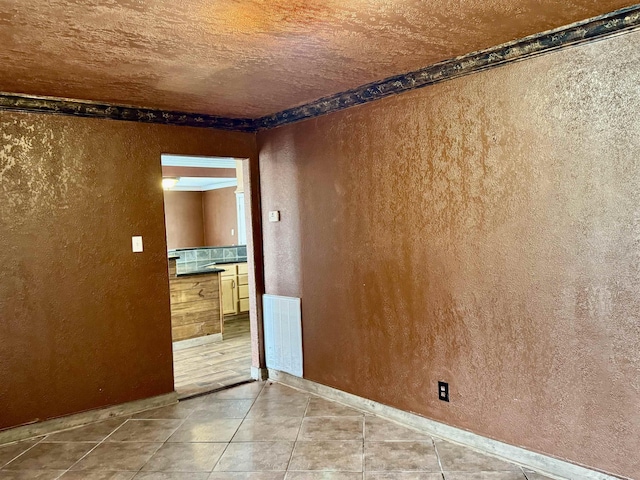 tiled empty room with baseboards, a textured wall, and visible vents