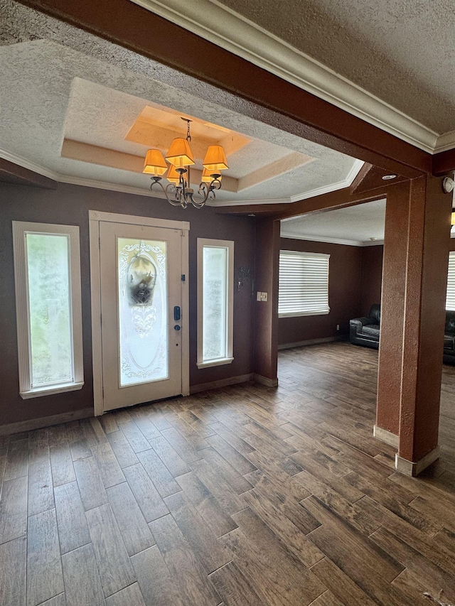 entryway with an inviting chandelier, crown molding, a tray ceiling, and a textured ceiling