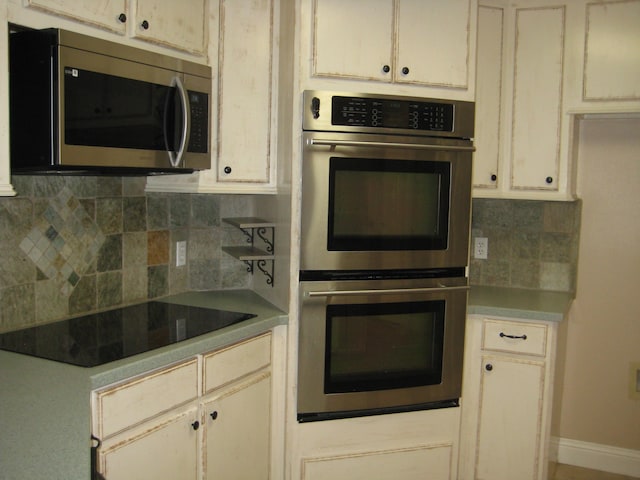 kitchen featuring tasteful backsplash, cream cabinetry, and appliances with stainless steel finishes