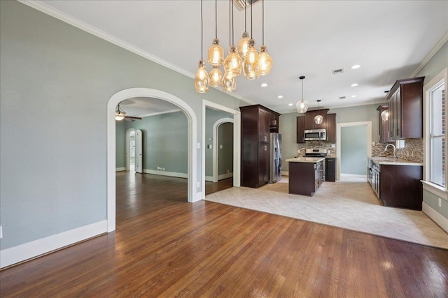 145 Manor St, Beaumont, TX 77706 - kitchen with stainless steel appliances, arched walkways, dark brown cabinetry, tasteful backsplash, and crown molding