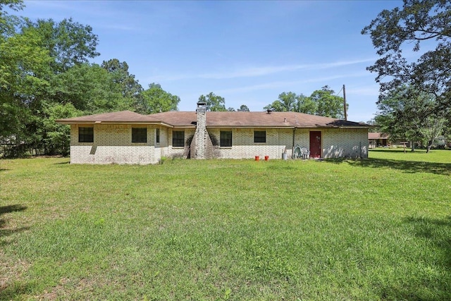 rear view of property featuring a chimney and a lawn